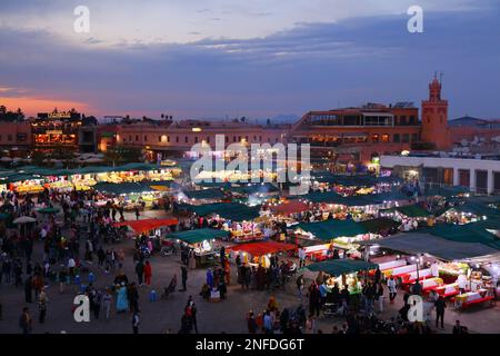MARRAKESCH, MAROKKO - 20. FEBRUAR 2022: Menschen besuchen den Markt auf dem Jemaa el-Fnaa-Platz in Marrakesch, Marokko. Der Platz ist als UNESCO-Masterpiec gelistet Stockfoto