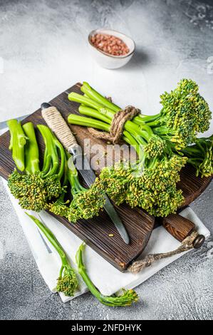 Frischer Broccolini-Sprossen auf dem Schneidebrett, bereit zum Kochen. Weißer Hintergrund. Draufsicht. Stockfoto