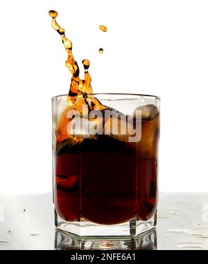 Ein Glas Cola mit Spritzer und Eiswürfeln auf Weiß Stockfoto