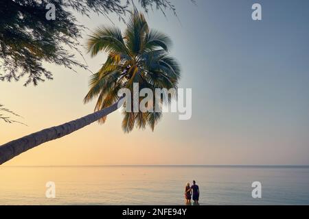 Glückliches Paar im Wasser am tropischen Strand in der Nähe von Palmen der Phi Phi Insel im Süden Thailands. Reisemagazin Urlaubskonzept. Stockfoto