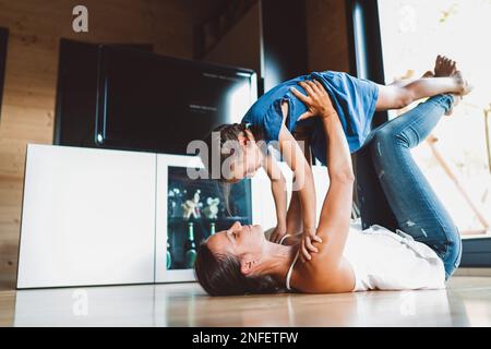 Mutter und Tochter haben Spaß beim Turnen zu Hause im Wohnzimmer Stockfoto