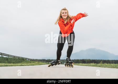 Blick von der jungen Frau in roter Jacke, die schnell auf die Kamera zugeht, mit einem großen Lächeln im Gesicht Stockfoto