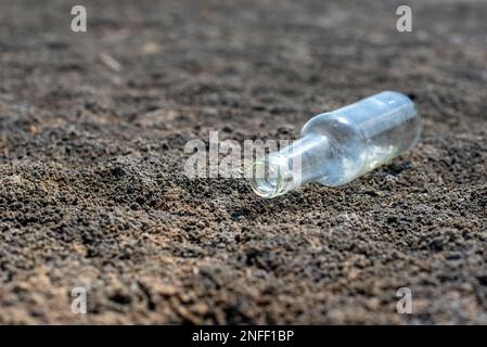 Glasflasche liegt auf dem Boden. Das Konzept des Wassermangels und der Dürre Stockfoto