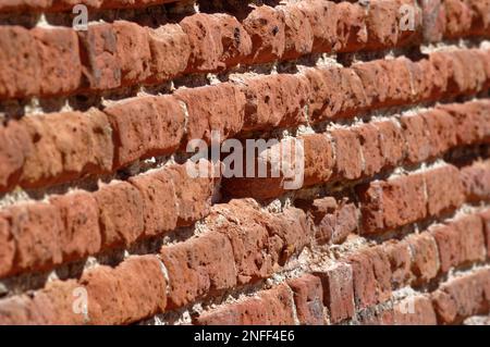 Alte, englische Bindung verlegte eine Ziegelmauer in schlechtem, erodiertem Zustand. Stockfoto