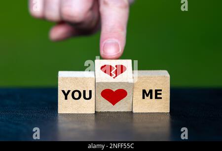 Symbol zum Aufbrechen einer Beziehung. Die Hand verwandelt einen hölzernen Würfel und verwandelt ein Herzsymbol in ein Symbol für gebrochenes Herz. Stockfoto