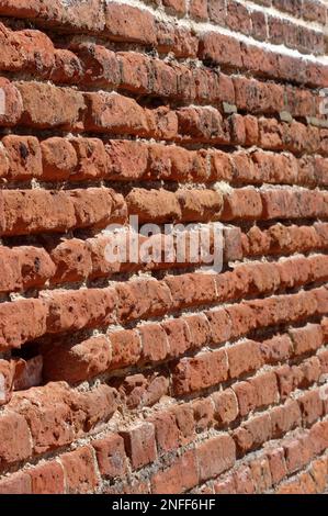 Alte, englische Bindung verlegte eine Ziegelmauer in schlechtem, erodiertem Zustand. Stockfoto