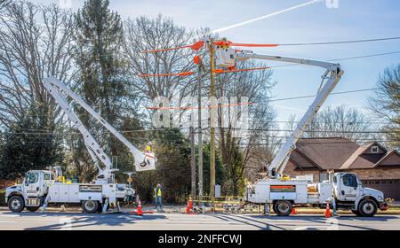 HICKORY, NC, USA-14. FEBRUAR 2023: Versorgungsarbeiter mit zwei Löffelwagen reparieren elektrische Leitungen. Stockfoto