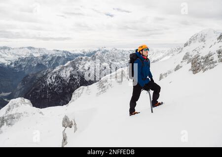 Wanderer mit Schutzhelm und Sonnenbrille blicken auf den schneebedeckten Berg Stockfoto