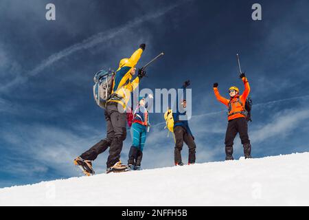 Eine Gruppe glücklicher Wanderer mit erhobenen Händen in der Luft, die sich freuen, den Gipfel des Berges zu erreichen Stockfoto