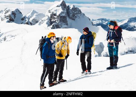 Eine Gruppe von vier Wanderern an einem sonnigen Tag in den schneebedeckten Bergen Stockfoto