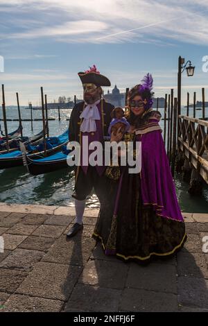 Karnevalsbesucher, gekleidet in prächtigen Kostümen und mit einer Maske, die den Hund während des Karnevals 2023 in Venedig im Februar am Markusplatz in Venedig, Italien, hielt Stockfoto