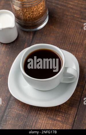 Instant- oder Granulatkaffee in einer weißen Tasse auf einem Holztisch Stockfoto