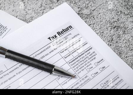 Steuererklärungsformulare für Finanzzeiten mit Stift auf einem Steintisch Stockfoto