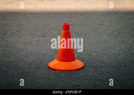 Orangefarbener Verkehrskegel auf dunklem Asphalt Stockfoto