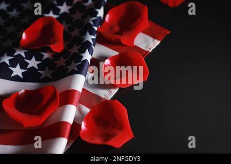 Amerikanische Flagge und Rosenblume auf dem Tisch. Symbol der Vereinigten Staaten von Amerika und rote Blütenblätter. Patriotismus und Erinnerung. Stockfoto