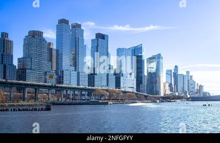 Wolkenkratzer, Gebäude entlang Henry Hudson Parkway und West Side Highway, Manhattan, New York City, an einem sonnigen Wintertag. Hudson River im Vordergrund. Stockfoto