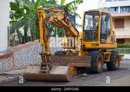 Gelber Hydraulikbagger auf einer Nebenstraße. Stockfoto