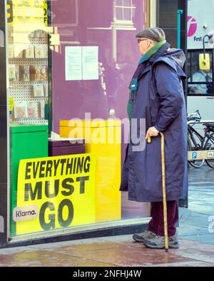 Glasgow, Schottland, Vereinigtes Königreich 17. Februar 2023. Papiere über die Art Meile des Bankrotts in der Buchanan Street, Postdetails und Verkaufsposter in ihrem Fenster, während ein alter Kunde sie liest... Credit Gerard Ferry/Alamy Live News Stockfoto