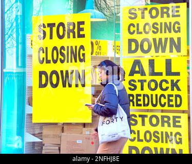 Glasgow, Schottland, Vereinigtes Königreich 17. Februar 2023. Papiere über die Art Meile des Bankrotts in der Buchanan Street, Postdetails und Verkaufsposter in ihrem Fenster, während ein alter Kunde sie liest... Credit Gerard Ferry/Alamy Live News Stockfoto