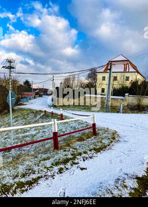Ein verschneiter Fußweg und ein großes Bauernhaus in der Slowakei. Stockfoto