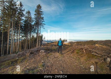 Reisende mit einem blauen Rucksack auf dem Rücken wandern zu seinen unvergesslichen Erlebnissen in den Beskydy-Bergen, Tschechische republik. Die Morgensonne leuchtet Stockfoto