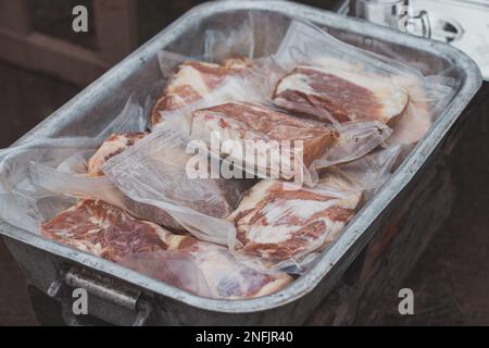 Mariniertes Rindfleisch in Öl, Knoblauch und Zwiebeln in einem versiegelten Beutel zur Zubereitung von Steak auf einem Grill im Freien. Biologisches Fleisch vom Metzger. Ich bereite mich auf die Woche vor Stockfoto