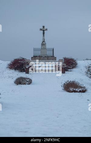 Ein vertikales Bild eines weißen Kreuzes auf einem Grab im Winter Stockfoto