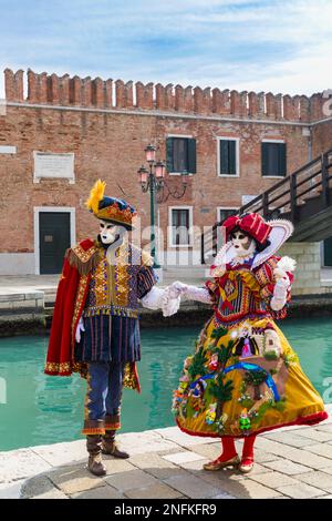 Karnevalsbesucher, gekleidet in prächtigen bunten Kostümen und Masken während des Karnevals 2023 in Arsenale, Venedig, Italien im Februar Stockfoto