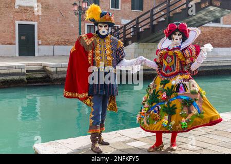 Karnevalsbesucher, gekleidet in prächtigen bunten Kostümen und Masken während des Karnevals 2023 in Arsenale, Venedig, Italien im Februar Stockfoto