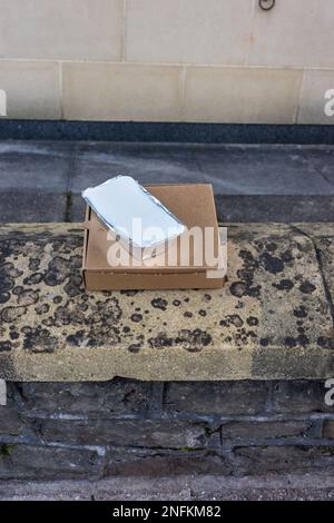 Einfache Pizzaschachtel zum Mitnehmen und Aluminiumschale an einer Ziegelwand Stockfoto