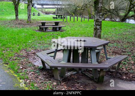 Leere Bänke mit Tischen für Touristen, die sich auf dem grünen Gras in der Nähe des Flusses ausruhen können. Ein Ort der Ruhe für Touristen und Reisende. Stockfoto