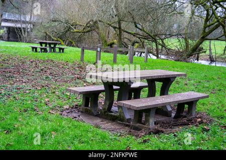 Leere Bänke mit Tischen für Touristen, die sich auf dem grünen Gras in der Nähe des Flusses ausruhen können. Ein Ort der Ruhe für Touristen und Reisende. Stockfoto