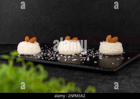 Köstliches Dessert cremiger Souffle, dekoriert mit Kokosnusschips und Nüssen auf dunklem Hintergrund Stockfoto