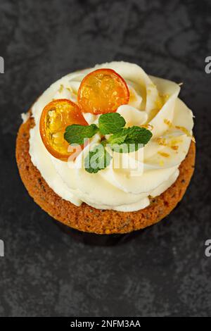 Cupcakes mit Käsesahne, dekoriert mit süßen Beeren auf dunklem Hintergrund Stockfoto