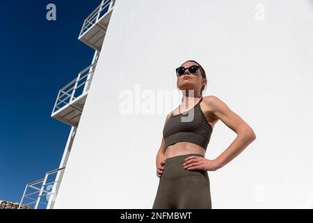 Nahaufnahmen von Frauen mittleren Alters in Sportkleidung mit Sonnenbrille, bereit, draußen in der Sonne zu trainieren Stockfoto