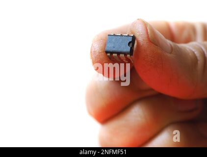 Bearbeitbare leere Chip-Oberfläche. Finger, die den elektronischen Chip auf isoliertem weißem Hintergrund halten. Stockfoto
