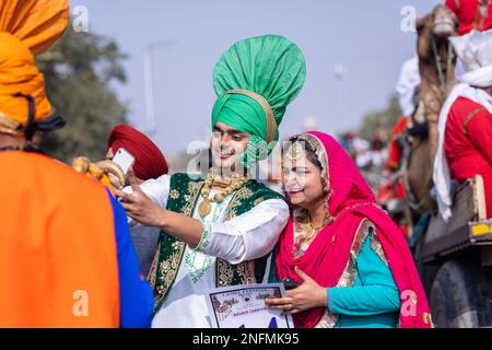 Punjabi Bhangra, Porträt des jungen sikh männlich in traditionellem punjabi farbenfrohem Kleid und Turban mit Bhangra-Tanz mit Lächeln im Kamelfestival. Stockfoto