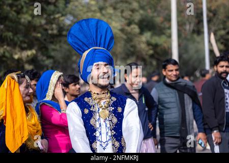 Punjabi Bhangra, Porträt des jungen sikh männlich in traditionellem punjabi farbenfrohem Kleid und Turban mit Bhangra-Tanz mit Lächeln im Kamelfestival. Stockfoto