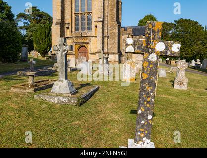 Außenansicht der St. Candida und Holy Cross Church mit abgenutzten Kreuzen im Friedhof, Whitchurch Canonicorum, Dorset, England, Großbritannien Stockfoto