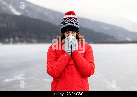 Frau trinkt heißen Tee nach Eislaufen auf einem gefrorenen See, Cerknica See, Slowenien Stockfoto