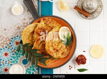 Roti Parata oder Roti Canai mit Lamm-Curry-Sauce und Zitrone, beliebtes malaysisches Frühstück Stockfoto