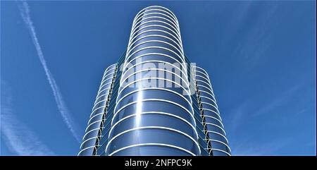 Vom Hubschrauber des modernen Wolkenkratzers mit runder Glasfassade aus betrachtet. Erstaunlicher blauer Himmel mit Flugzeugstreifen. 3D-Rendering. Stockfoto