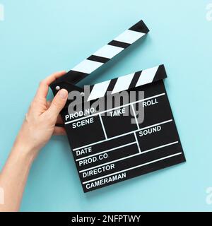 Person mit blauem Hintergrund und Filmklapper Stockfoto