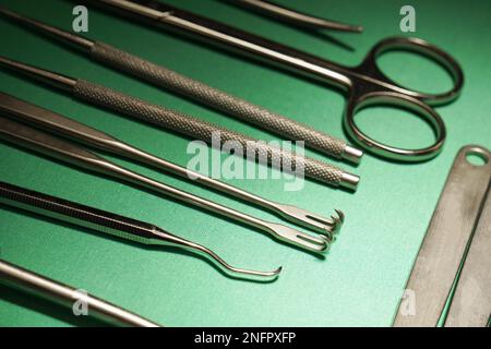 Verschiedene chirurgische Instrumente auf grünem Krankenhausdrapieren Stockfoto