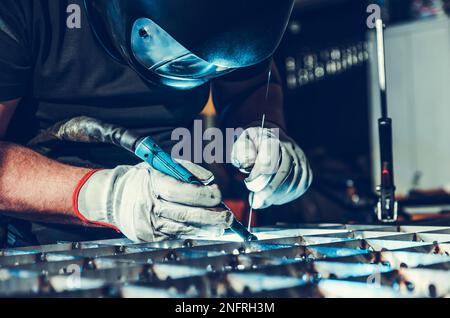 Nahaufnahme des professionellen Schweißers im Schutzhelm beim WIG-Schweißen. Thema „Industrieproduktion und Fertigung“. Stockfoto