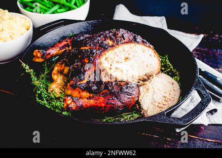 Hähnchen mit Apfel-Butter-Braten mit Schnitzmesser und Gabel: Gebratenes Hähnchen in einer Gusseisenpfanne mit Kartoffelpüree und grünen Bohnen Stockfoto