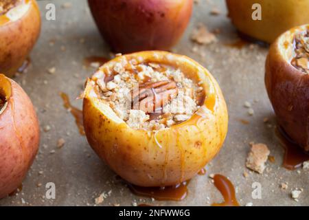 Käsekuchen gefüllte Äpfel, garniert mit Karamellsauce: Gebackene Äpfel mit Zimt-Sahne-Käsefüllung, garniert mit Pekannüssen Stockfoto