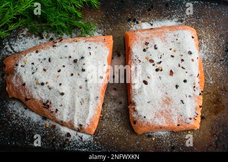 Lachsfilets bedeckt mit Meersalz und Gewürzen zur Herstellung von Lox: Lachsfilets bedeckt mit Meersalz auf einer Pfanne zur Herstellung von hausgemachtem Lachs Stockfoto