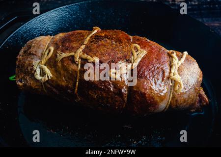 Gefülltes Flankensteak mit Prosciutto und Pilzen in der Pfanne: Unverschnittenes Steak Roulade mit Küchenschnur in einer gusseisernen Pfanne Stockfoto