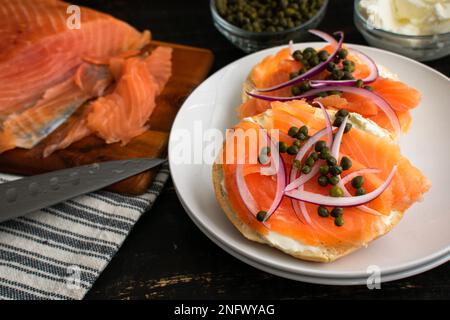 Bagelscheiben garniert mit Lox, Zwiebeln, Kapern und Frischkäse: Scheiben geräucherten Lachses mit verschiedenen Garnierungen auf einem einfachen Bagel Stockfoto